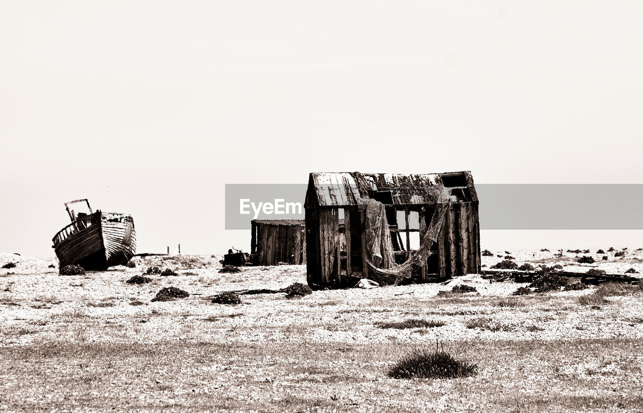 OLD ABANDONED VEHICLE ON FIELD AGAINST CLEAR SKY