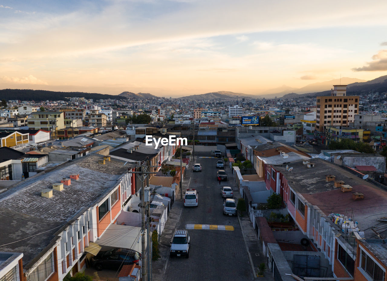 HIGH ANGLE VIEW OF ROAD AMIDST BUILDINGS AGAINST SKY