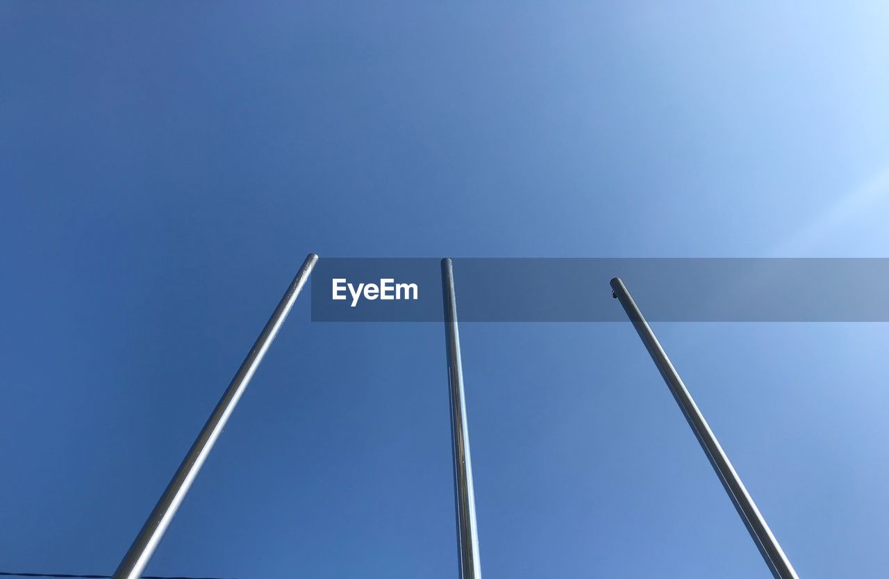 Low angle view of flagpole against clear blue sky