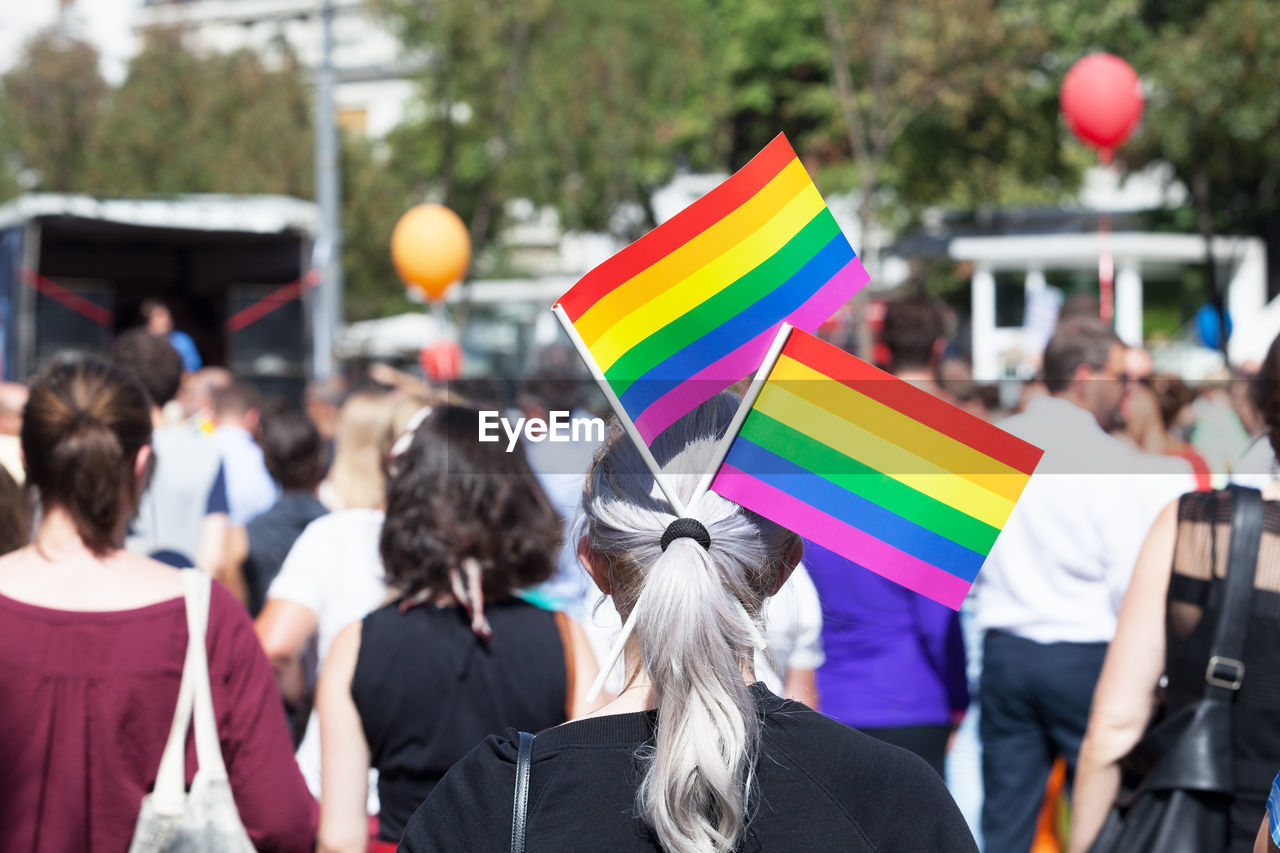 Rear view of woman with rainbow flags in hair on street