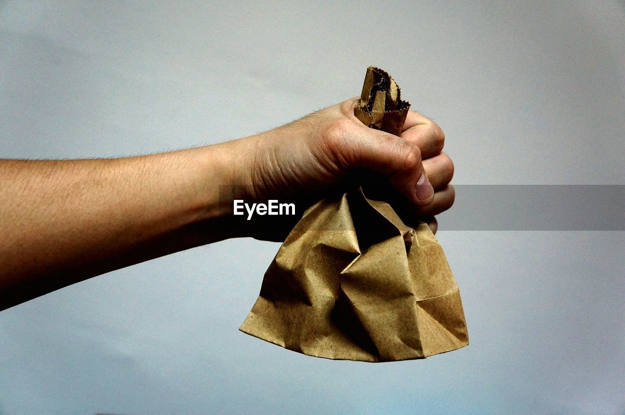 Close-up of cropped hand holding brown paper bag