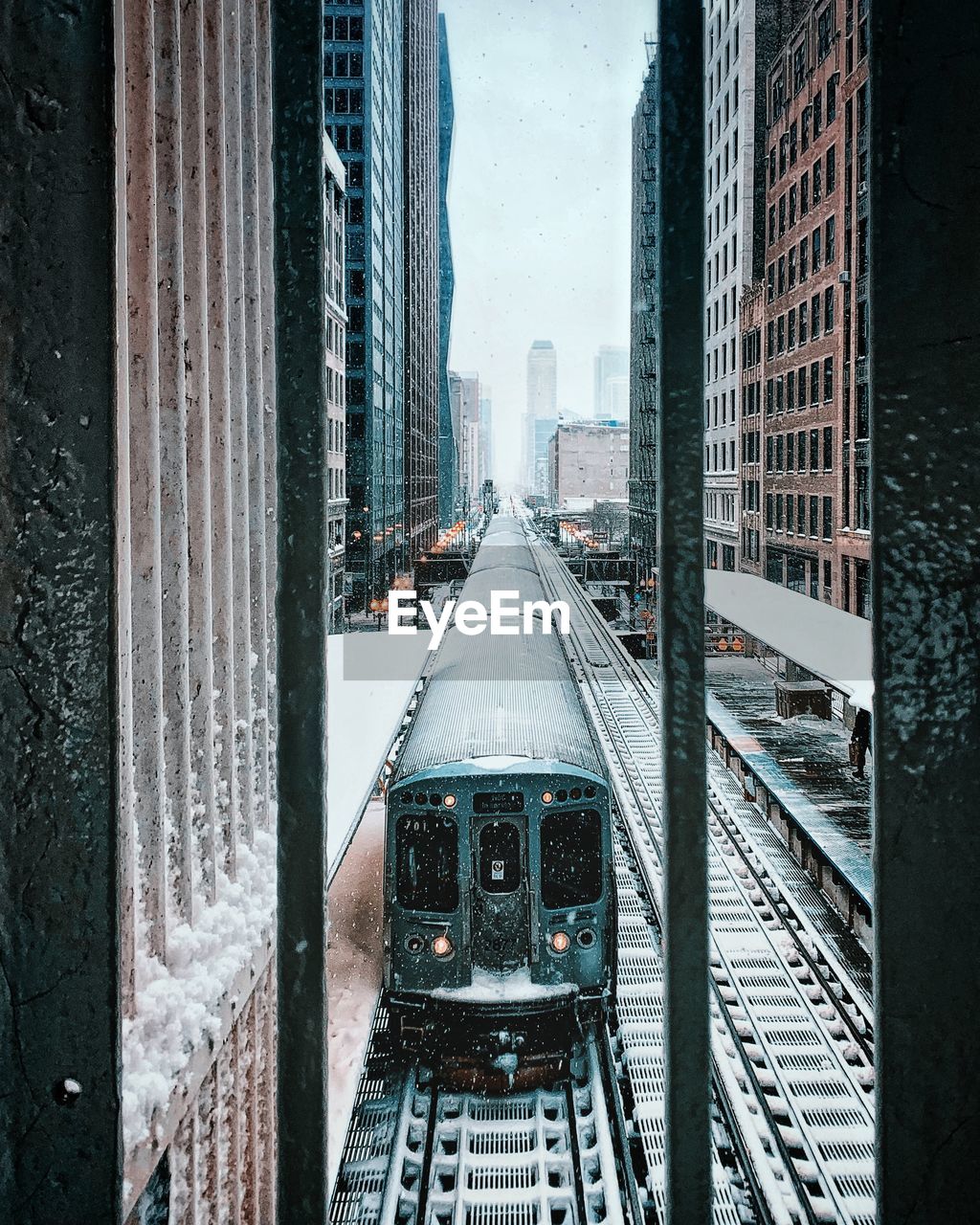 RAILROAD TRACKS AMIDST BUILDINGS DURING WINTER