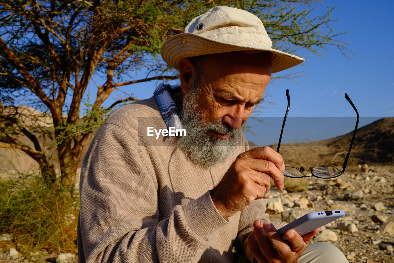 Side view of senior man using mobile phone