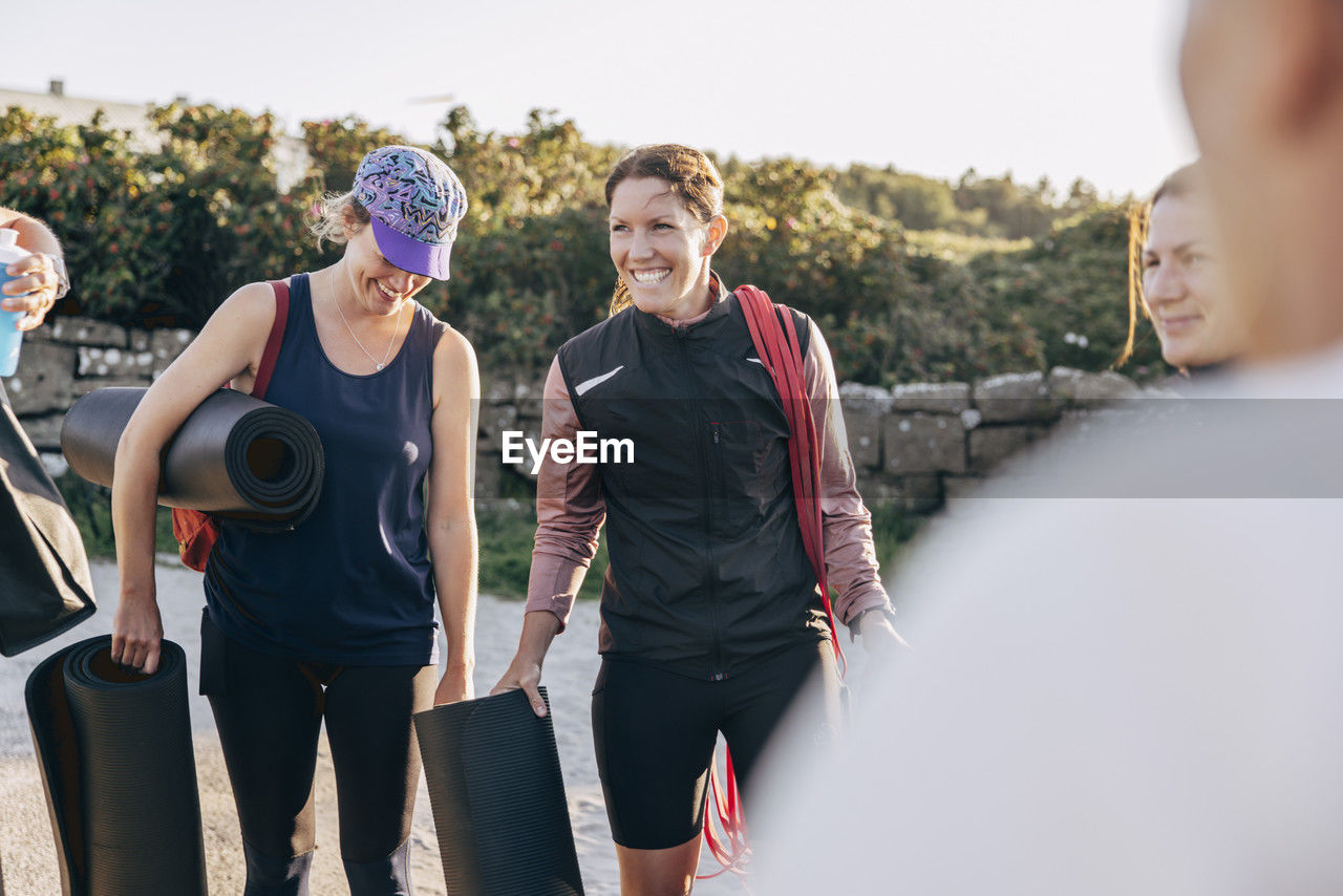 Happy women carrying exercise mats during group training session