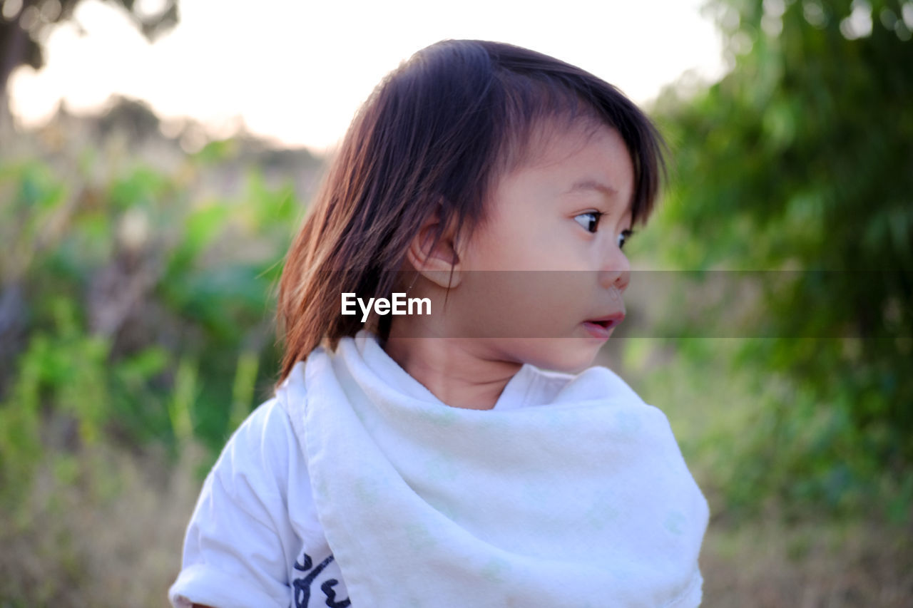 CLOSE-UP PORTRAIT OF CUTE GIRL LOOKING AWAY OUTDOORS