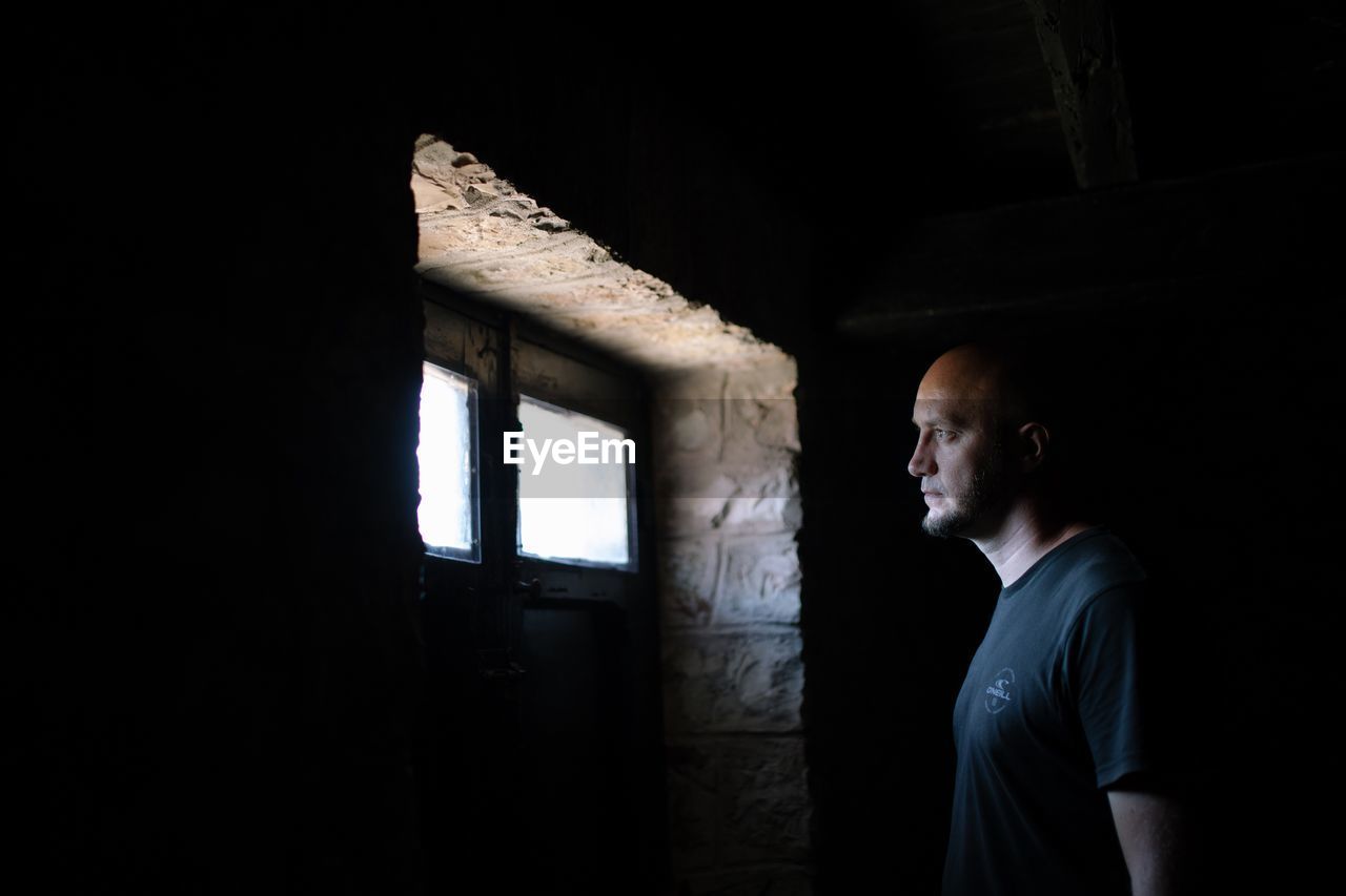 Thoughtful man standing in darkroom