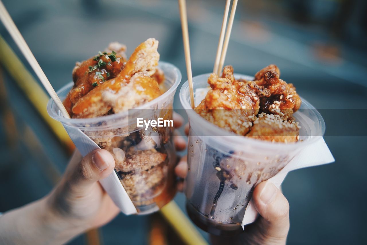 Close-up of hand holding food in disposable glasses outdoors