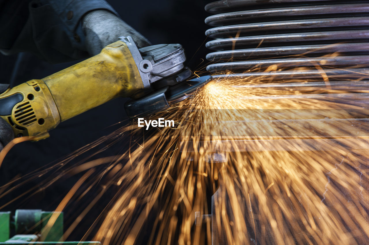 Close-up of worker using angle grinder in a factory