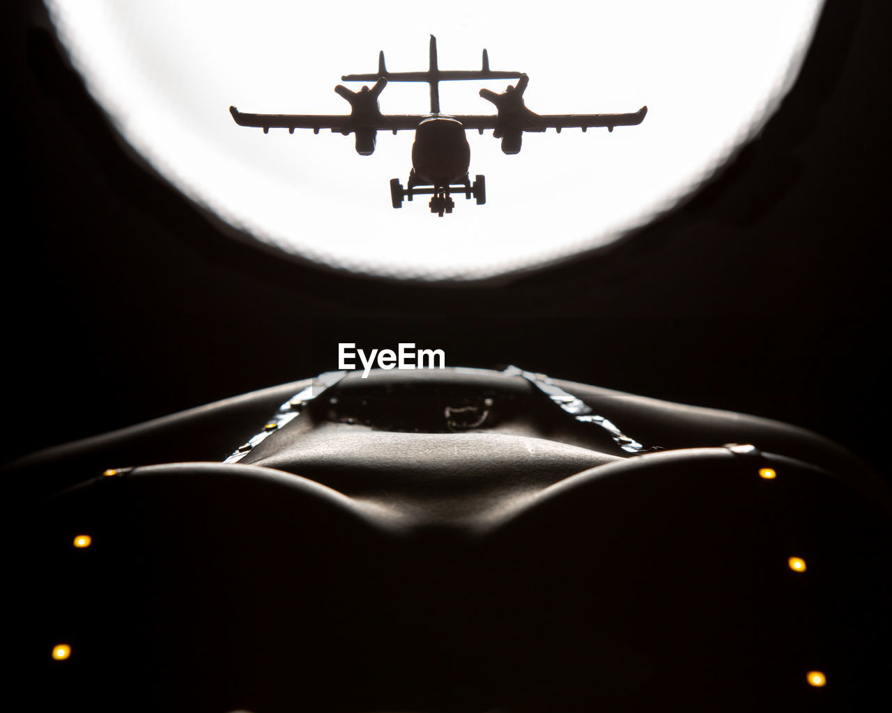 LOW ANGLE VIEW OF AIRPLANE IN MID-AIR OVER DARK BACKGROUND