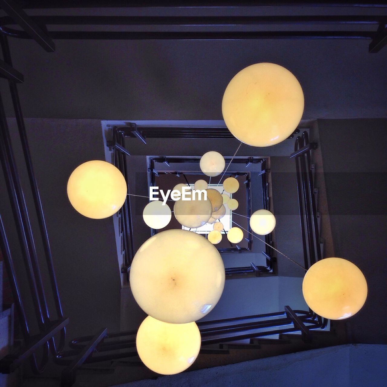 Directly below view of hanging lights surrounded by staircase