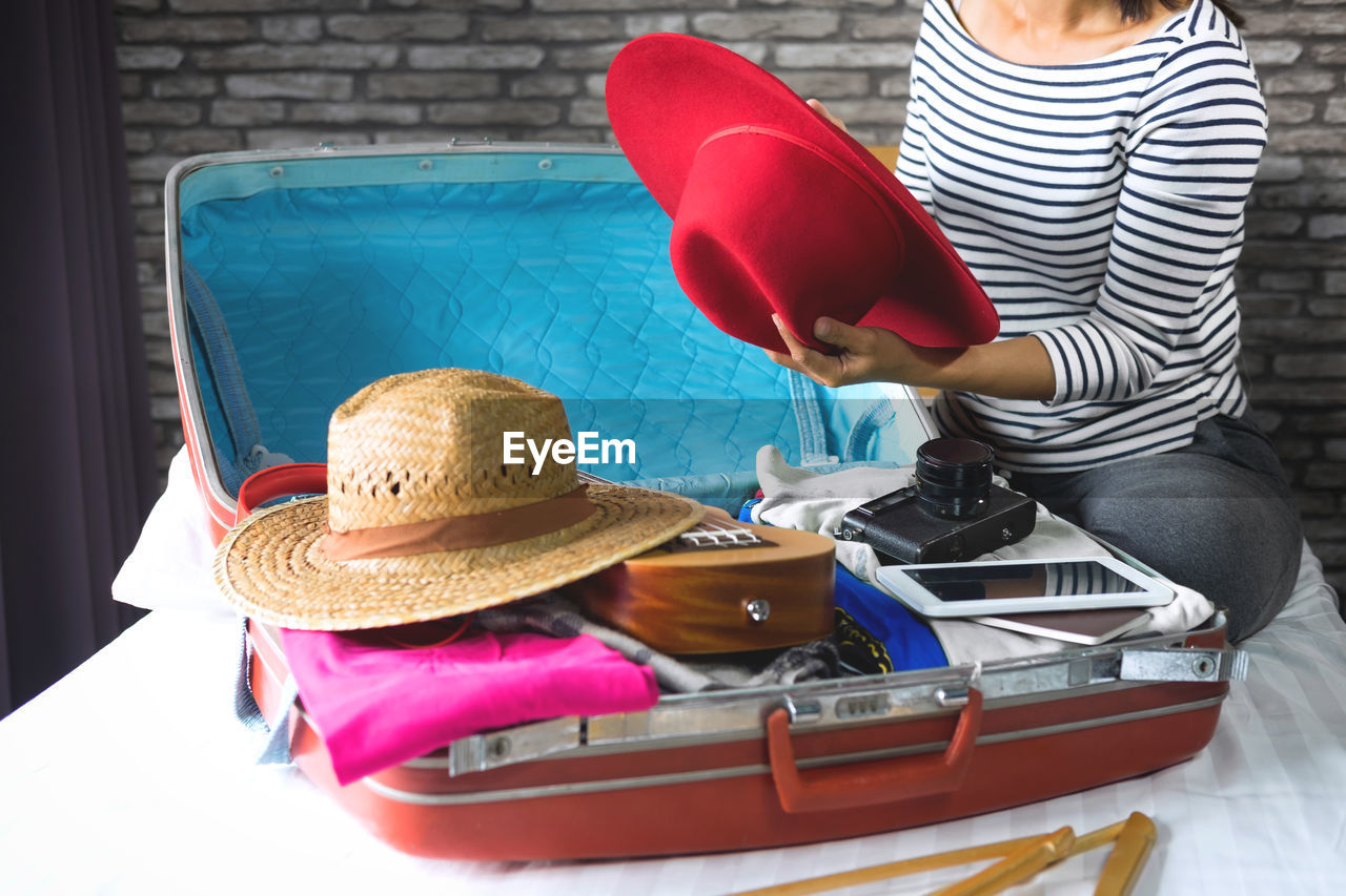 Low section of woman packing luggage at home