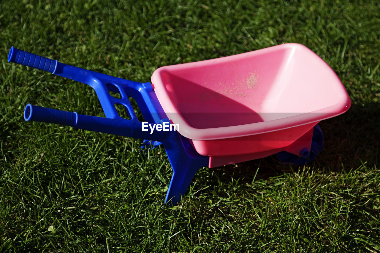 Pink toy wheelbarrow on green grass