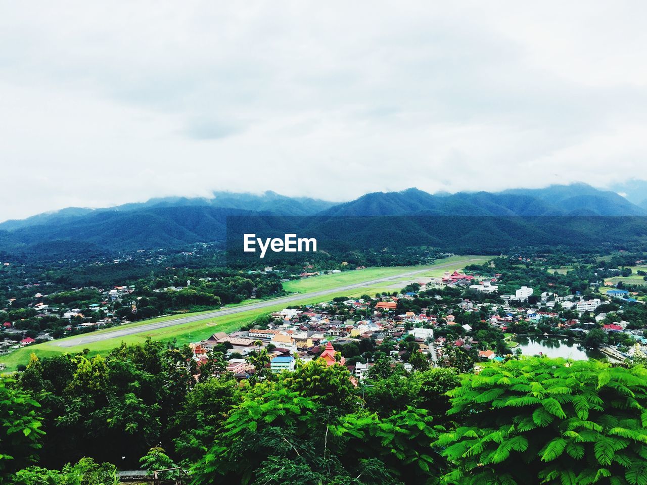AERIAL VIEW OF TOWNSCAPE BY MOUNTAIN AGAINST SKY
