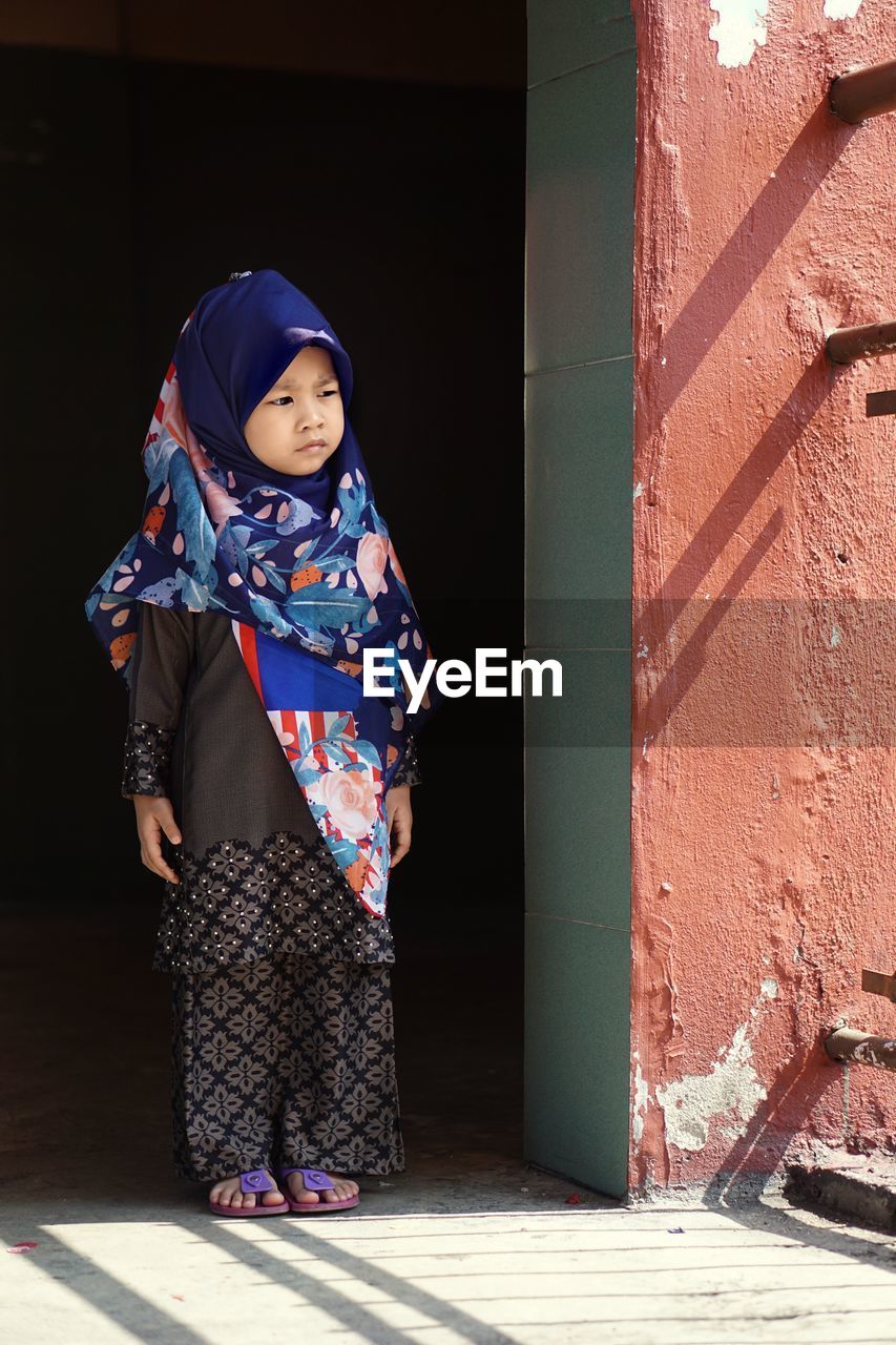 Hijab -wearing children stare outside the house
