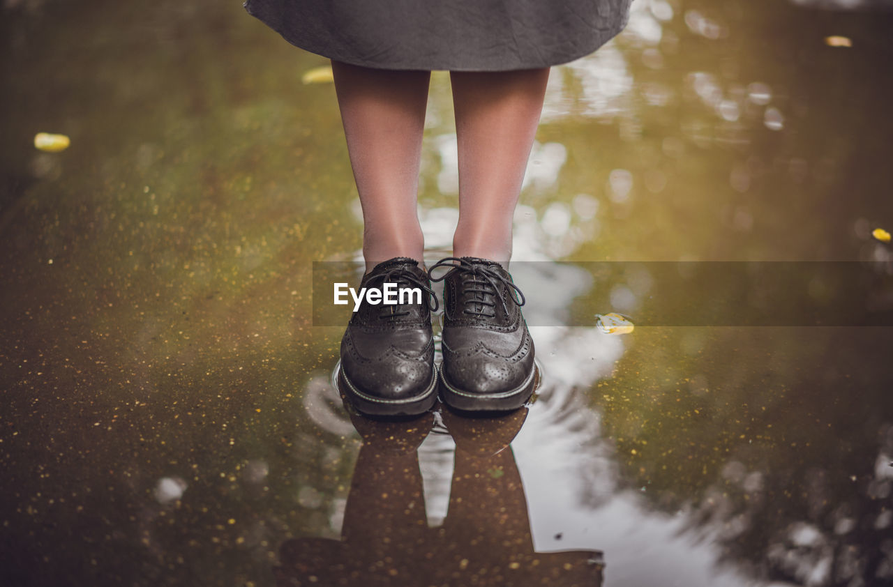 Low section of woman standing on puddle