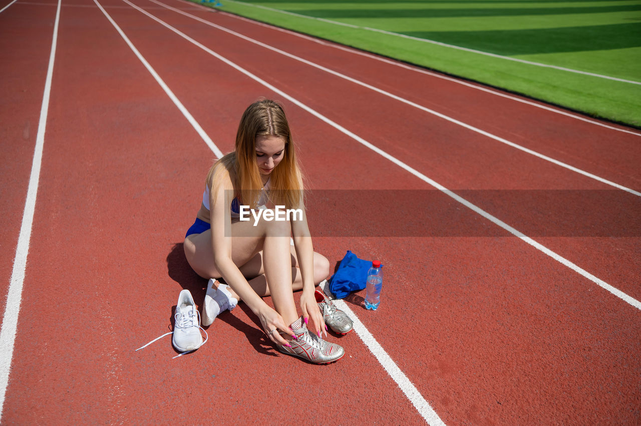 full length of young woman sitting on road