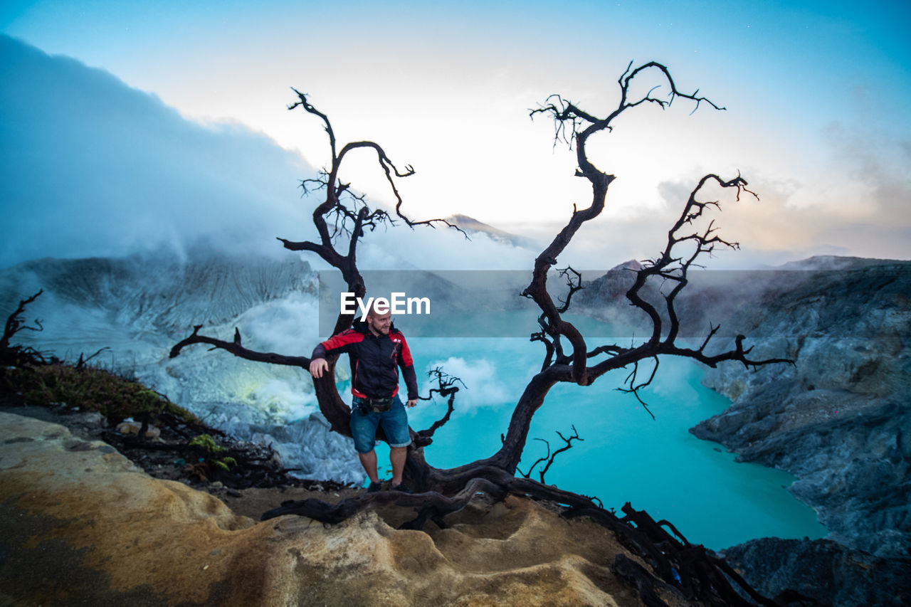 MAN ON ROCK BY MOUNTAIN