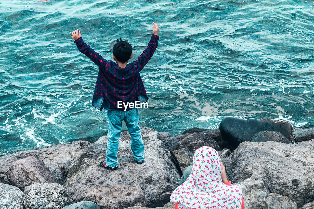 High angle view of woman and boy on rocks by sea