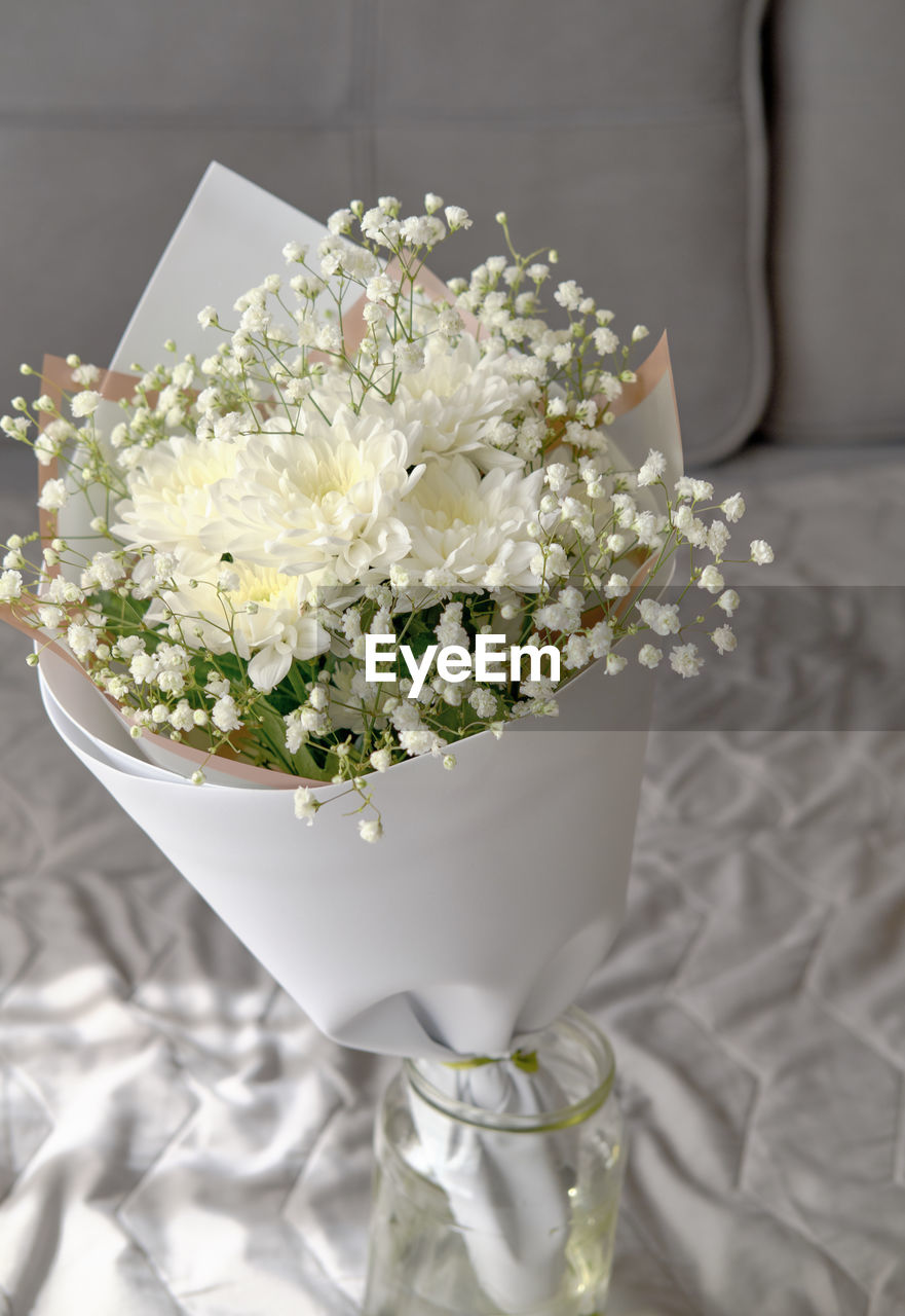 Bouquet of white chrysanthemums and gypsophila wrapped in craft paper. 