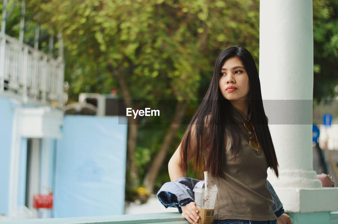 portrait of young woman standing against buildings in city