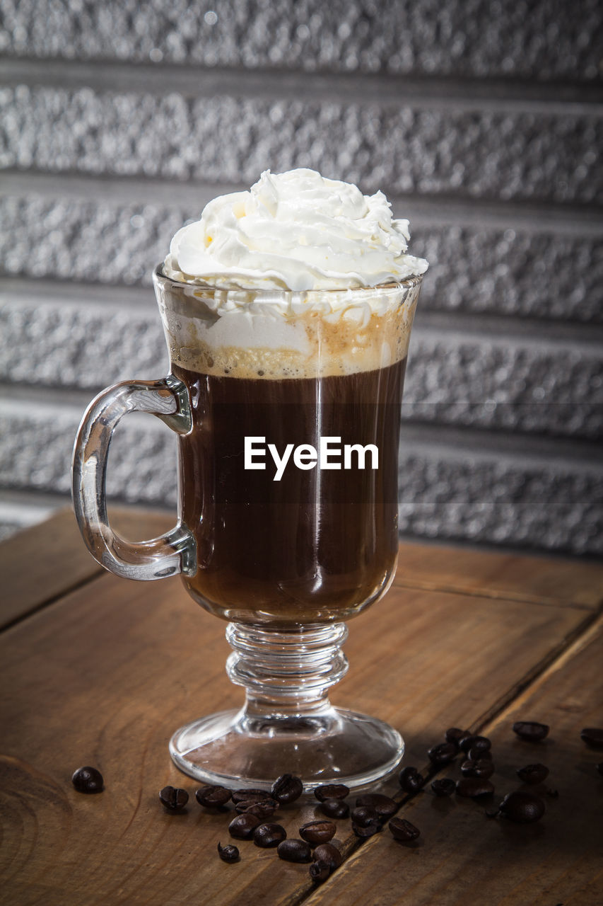 Close-up of coffee with whipped cream on wooden table