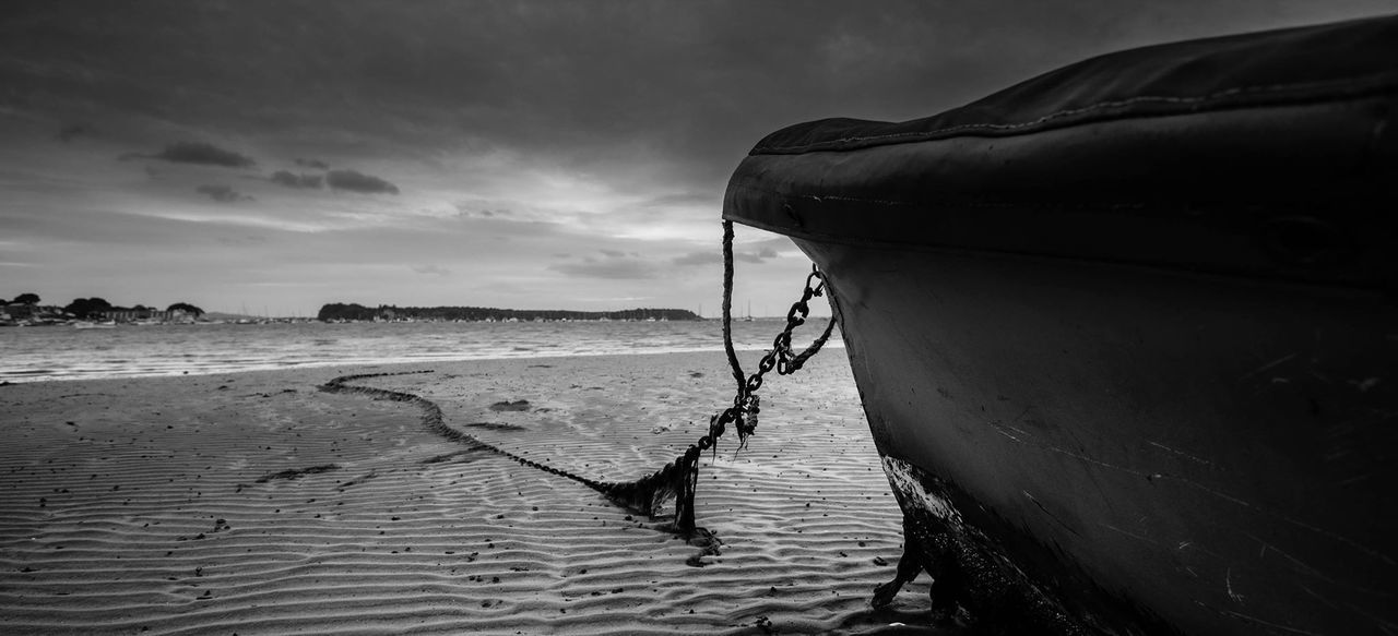 Cropped image of boat moored on beach against sky