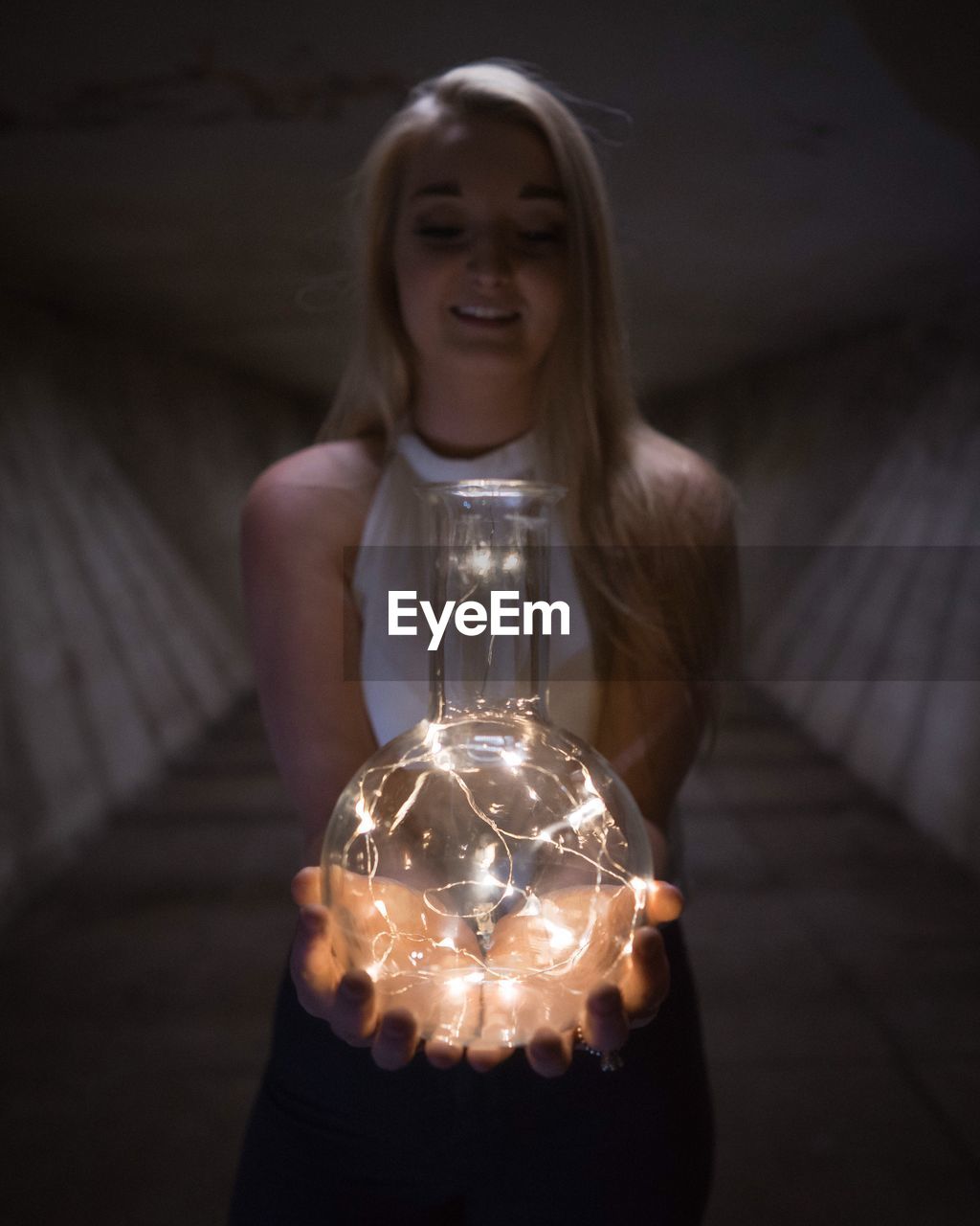 CLOSE-UP OF YOUNG WOMAN HOLDING LIGHT BULB ON MIRROR