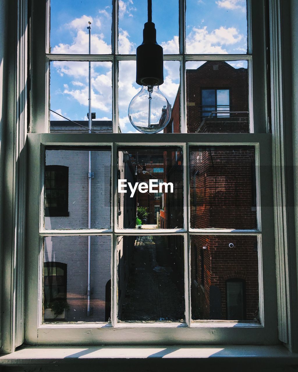 Light bulb hanging against glass window