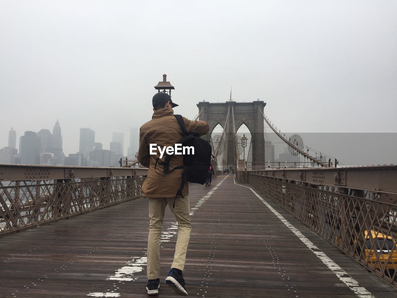 REAR VIEW OF PEOPLE ON FOOTBRIDGE IN FOGGY WEATHER