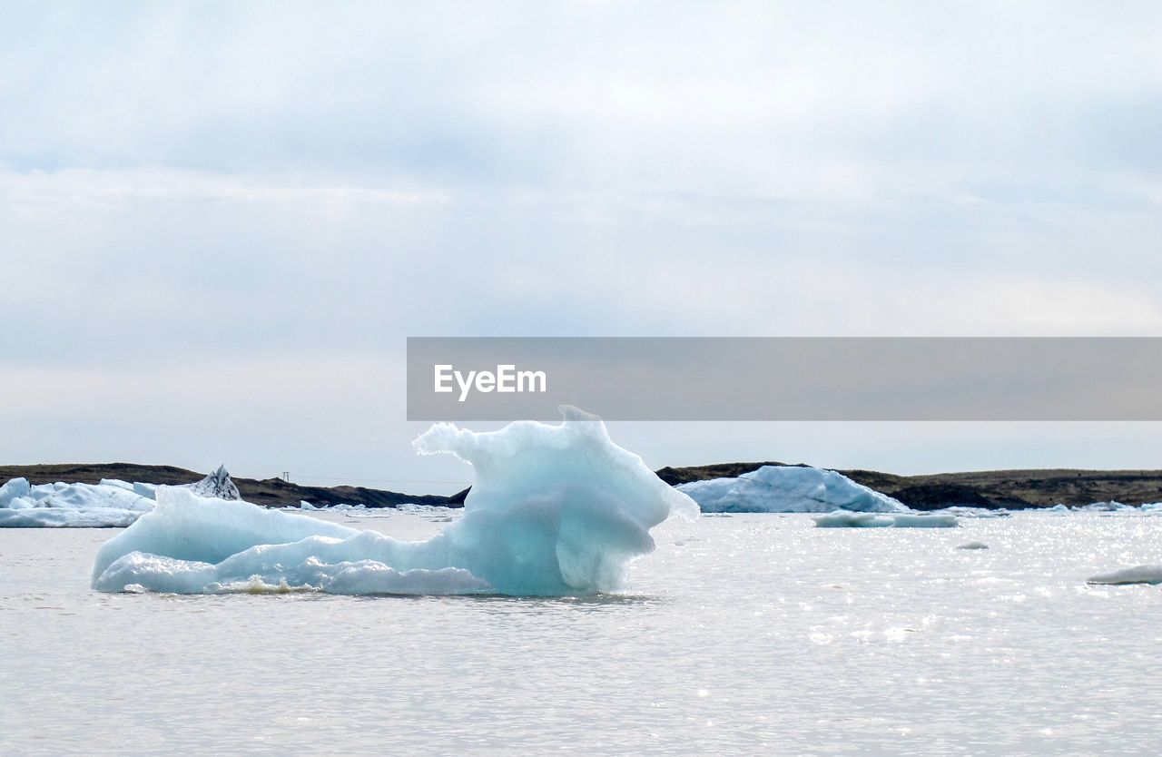 Ice floating in sea against sky during winter