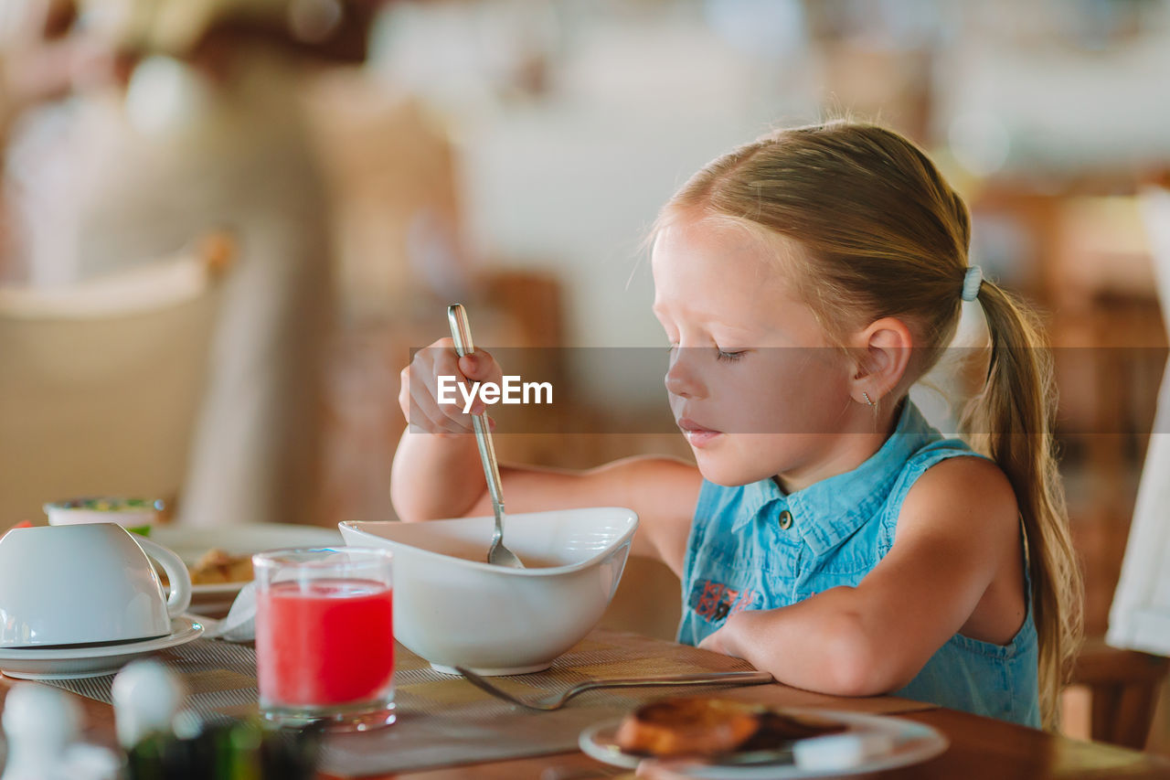 Close-up of girl eating food at home