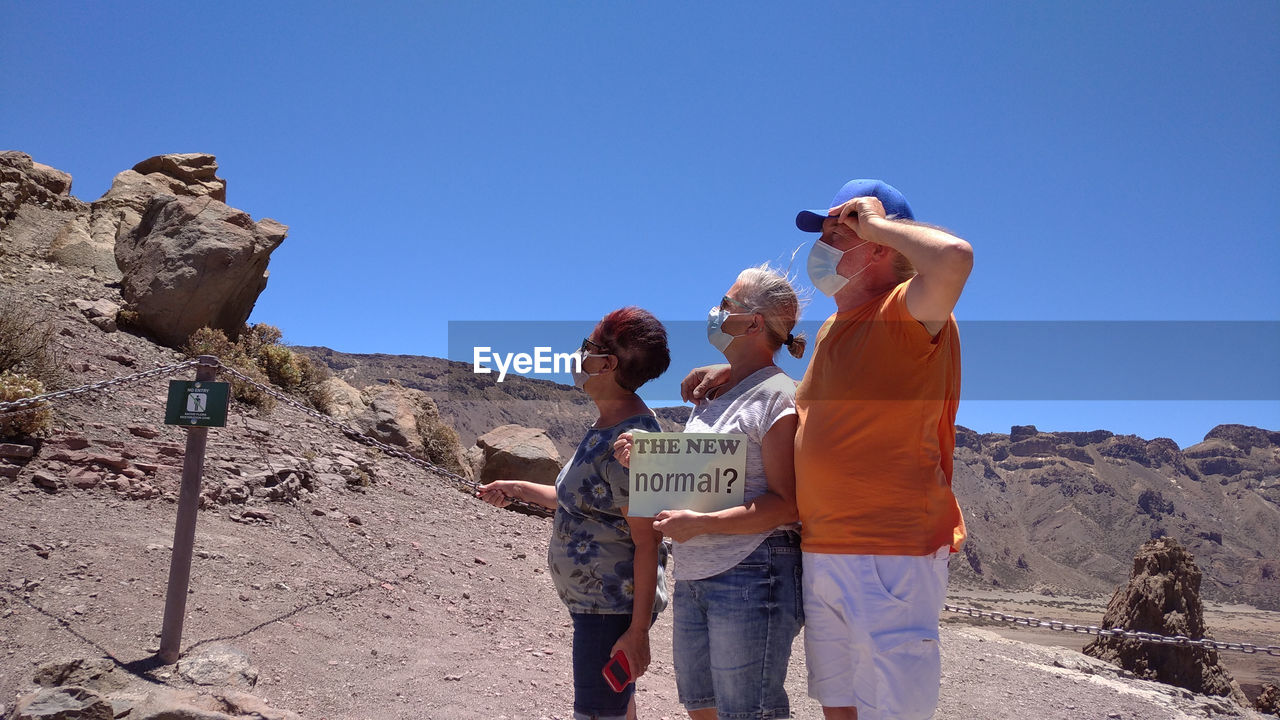 People standing on land against mountains and sky