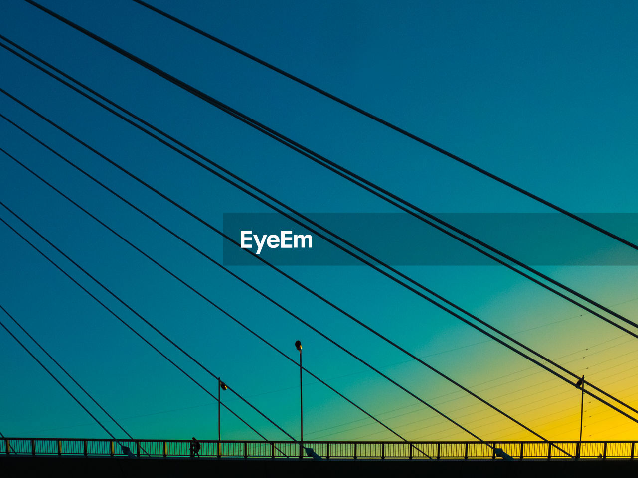 View of suspension bridge cables against sky at sunset