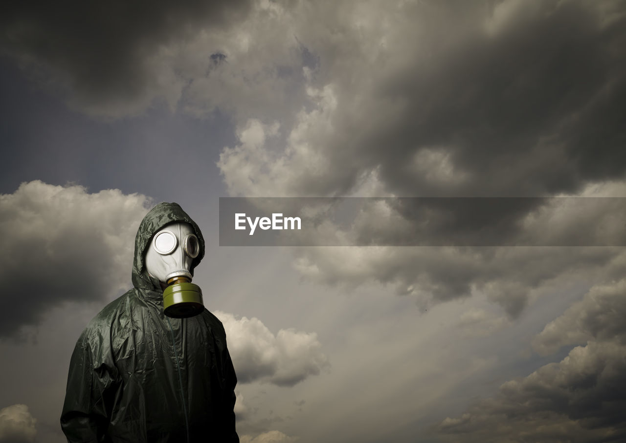 rear view of man wearing hat standing against cloudy sky