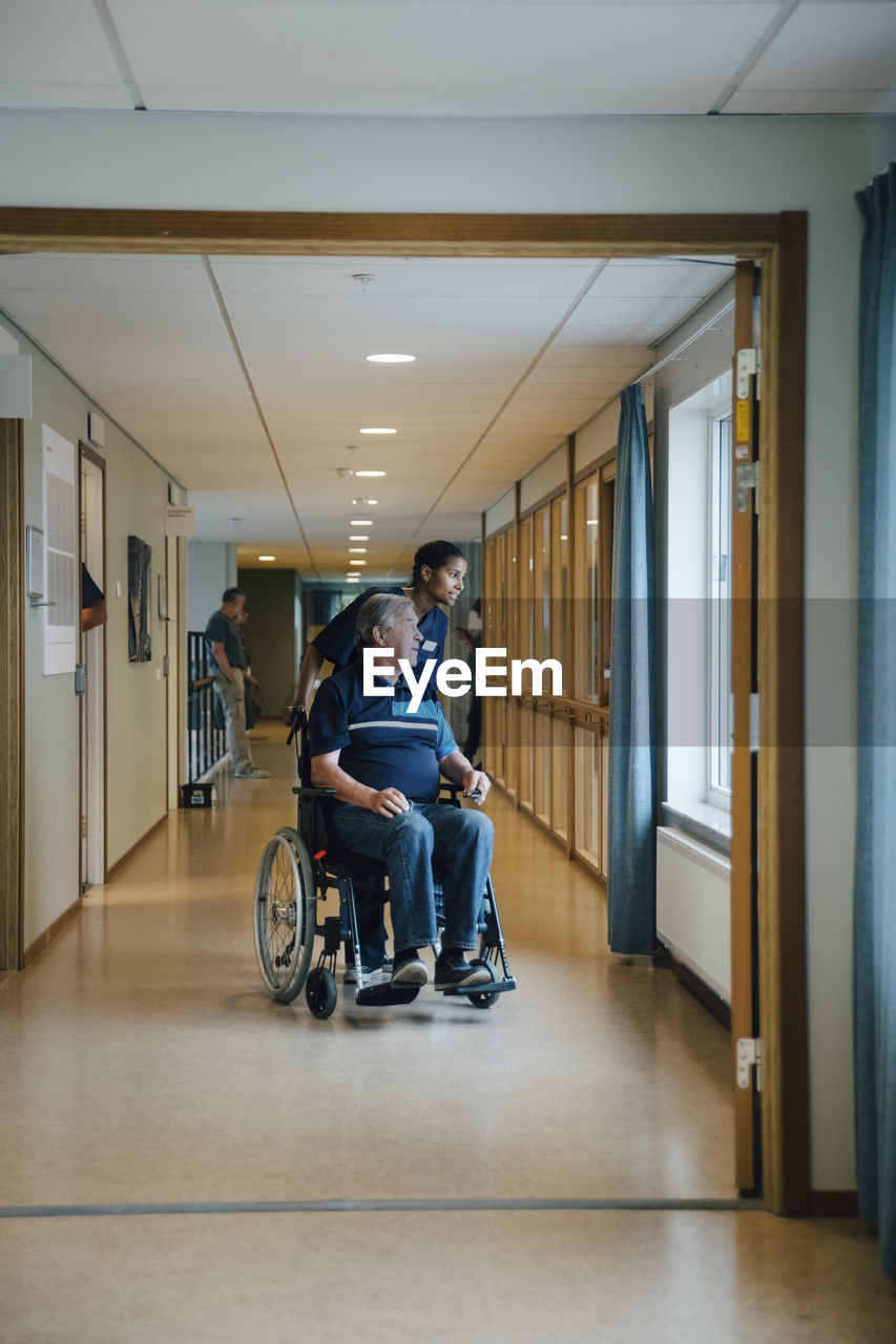 VIEW OF PEOPLE SITTING IN CORRIDOR OF BUILDING