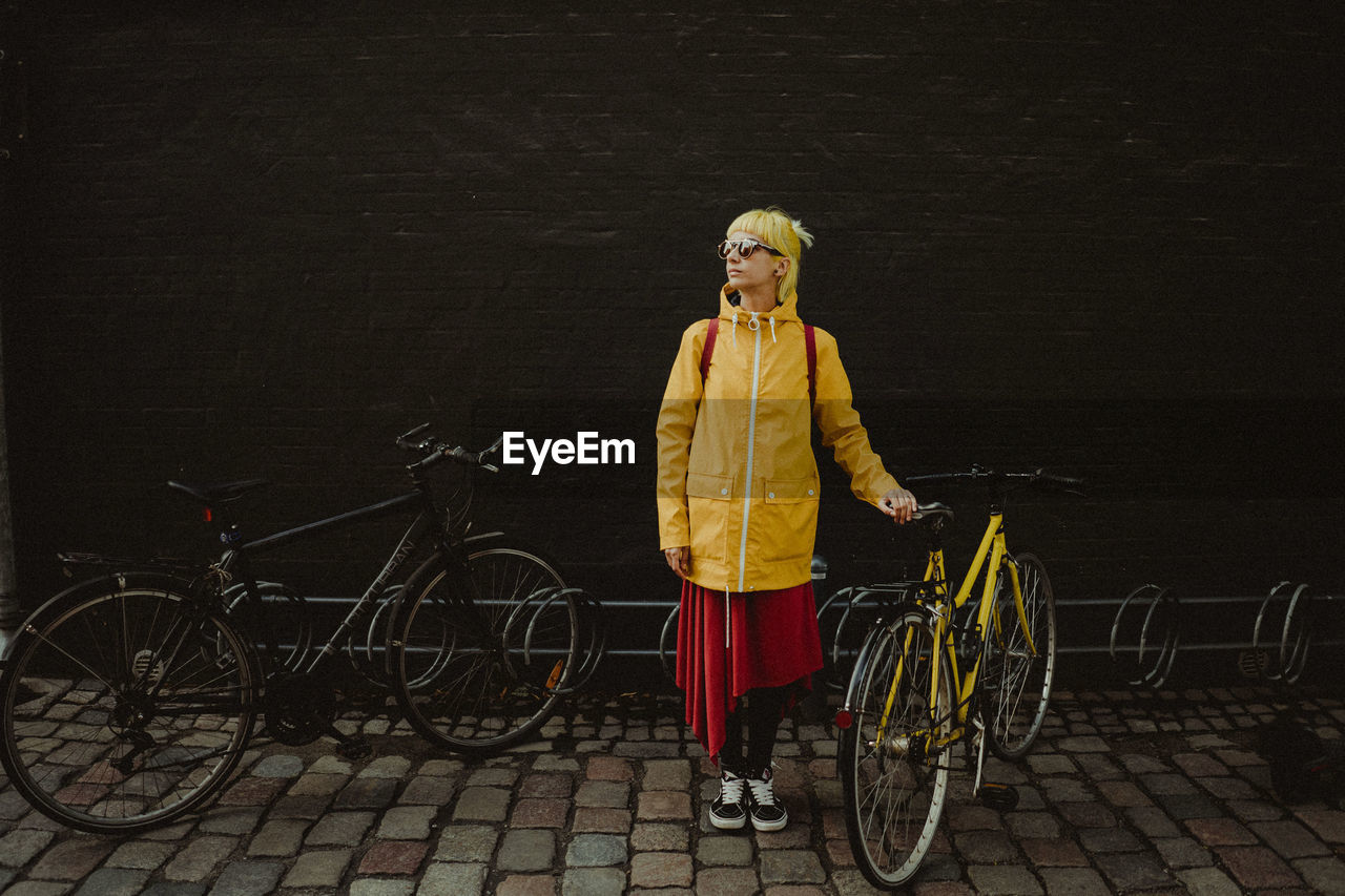 Young girl with bicycle standing on street