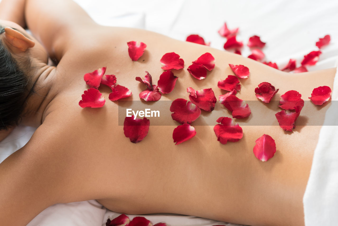 Rear view of woman with roses on back lying at health spa