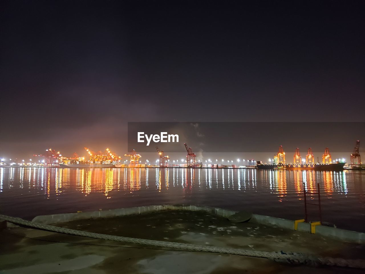 PANORAMIC VIEW OF ILLUMINATED CITY BY SEA AGAINST SKY