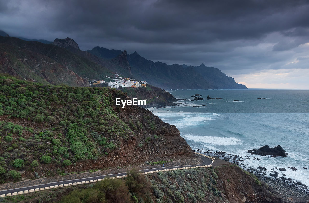 Scenic view of mountains by sea against cloudy sky