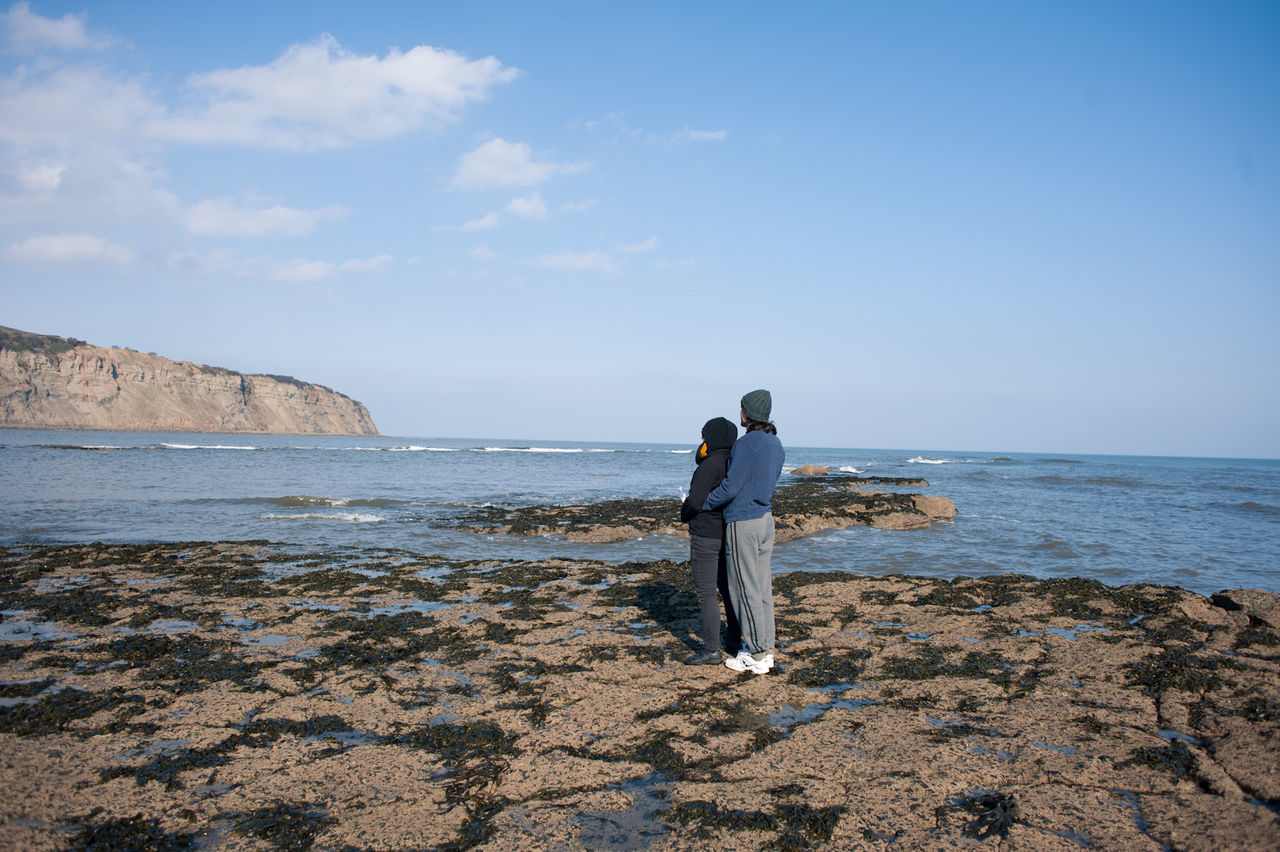 Couple looking at sea against sky