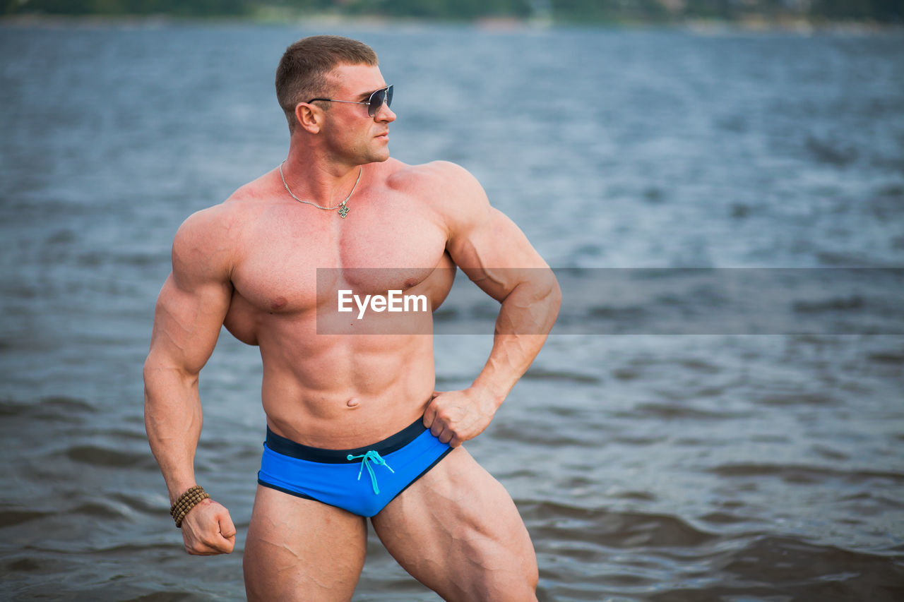 Shirtless bodybuilder while standing in sea