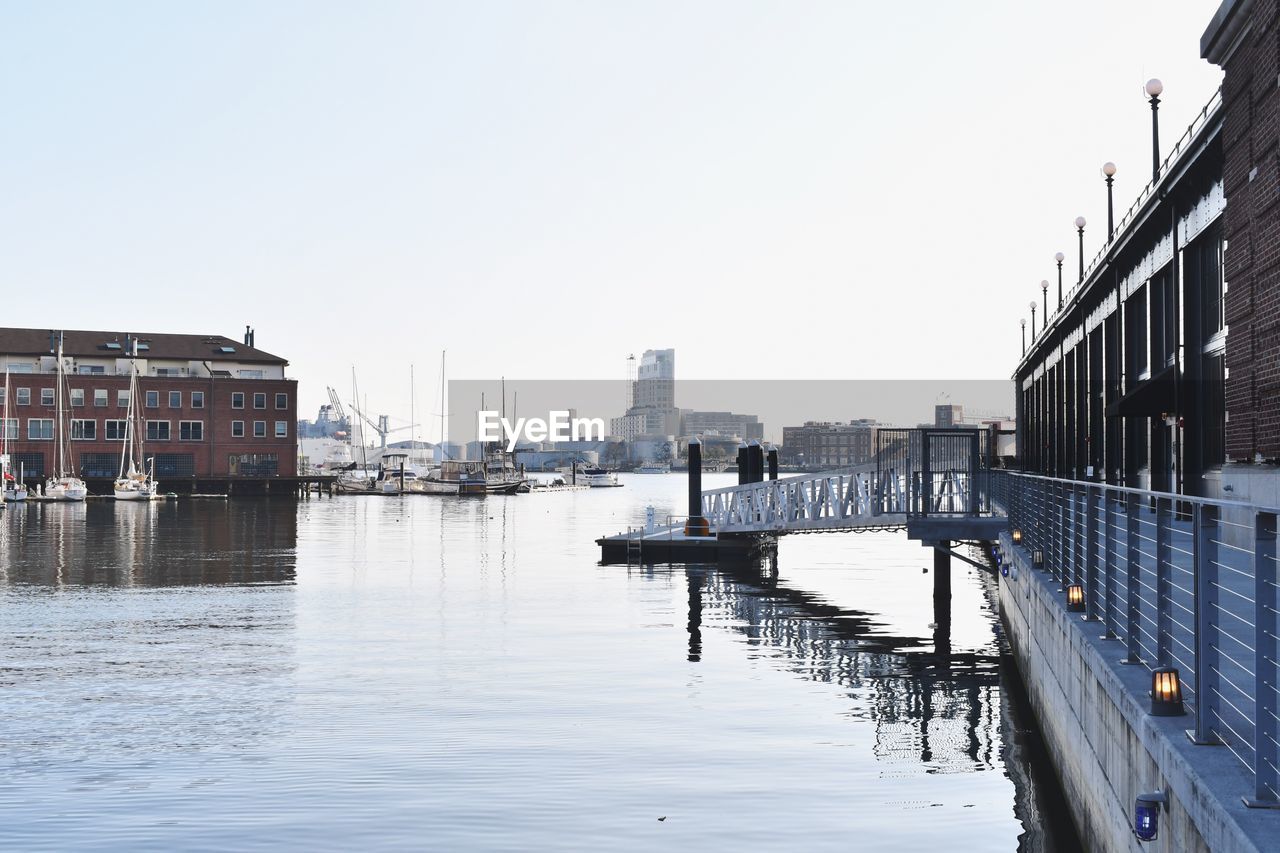 Buildings by river against sky in city