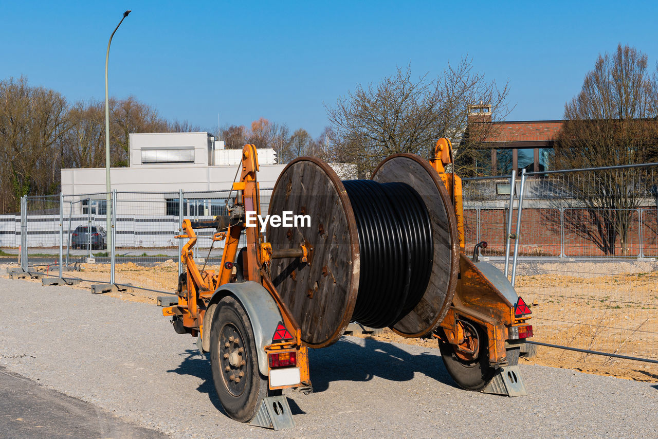 A wooden reel with an electric cable is mounted on a two-wheeled trailer. construction site. 