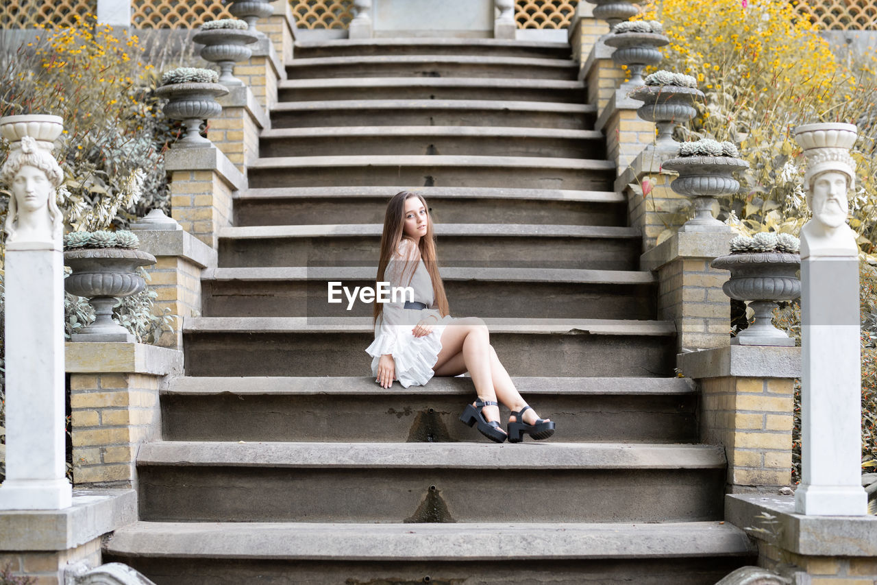 Full length of young woman sitting on staircase