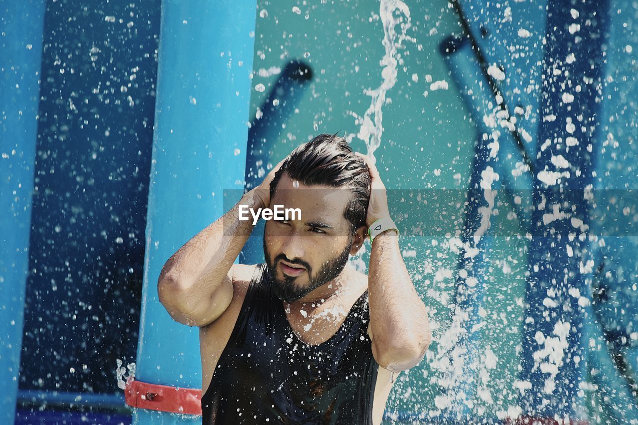 PORTRAIT OF YOUNG MAN WITH SWIMMING POOL