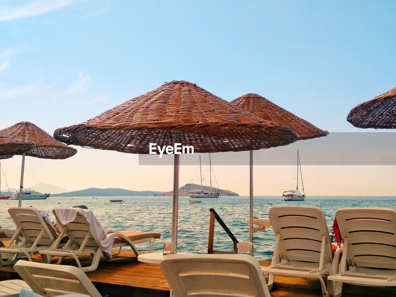 LOUNGE CHAIRS AND TABLES ON BEACH AGAINST SKY