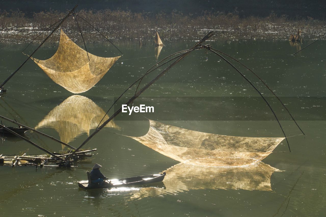Man sailing boat by chinese fishing nets in lake