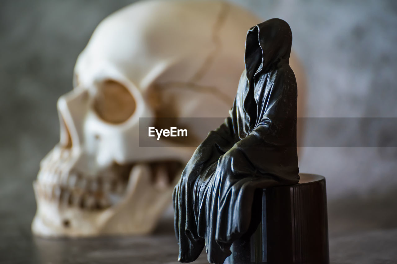 sculpture, art, statue, indoors, bone, black, death, close-up, focus on foreground, no people, figurine