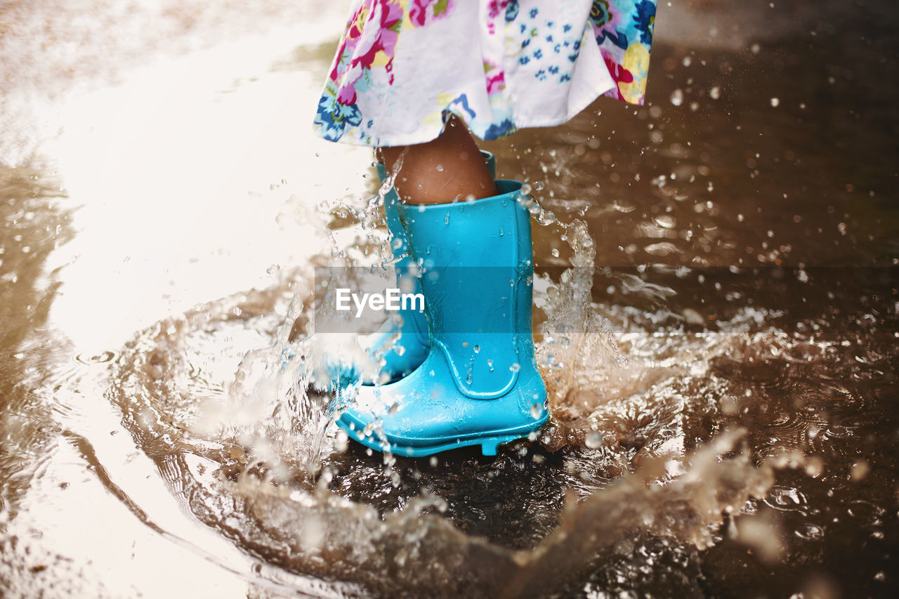 Low section of girl splashing on water