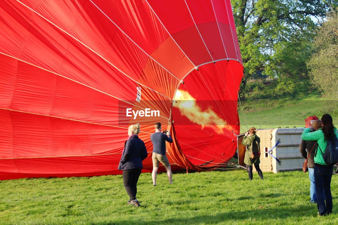 People standing by hot air balloon on grassy field